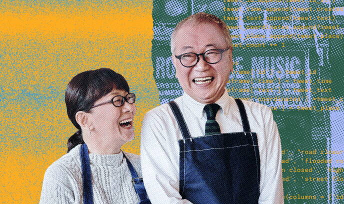 レストランのエプロンをした年配の男性と女性が料理のメニューを前に笑顔を見せている画像